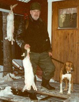 Uno Olsson med två harar som vi fixat vid en harjakt den 1/12 1990. Hunden är XX Soitinkorven Kallma och dörren till stugan är dörren till Unos vinterstuga på Bergnäsudden, en udde ut i Kalix älven. Trevlig jaktdag som etsat sig fast. Kallma är farmor till Essis far. Likheter mellan Kallma o Essi.
